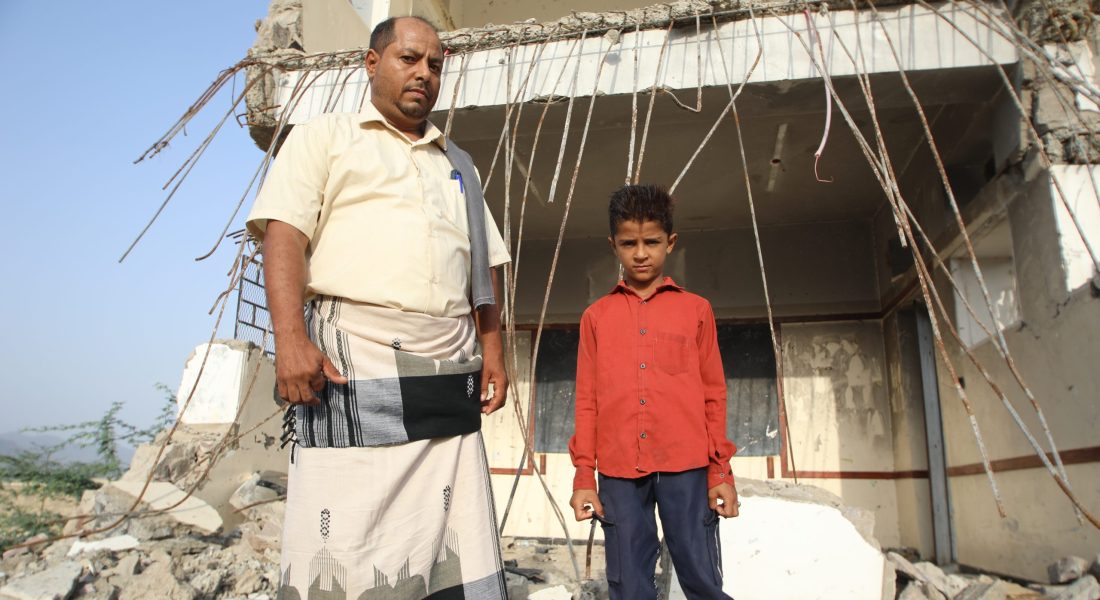 Headmaster of Akaad Shaab School, Ahmad Mohamad Al Aarakani and his son Marwan pose in front of a destroyed classroom